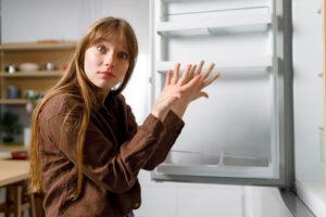 depicts young woman reacting badly to fridge because of food allergies