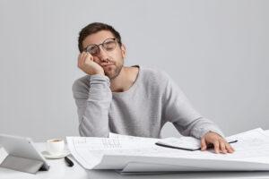 tired man with adrenal fatigue at desk doing paperwork 
